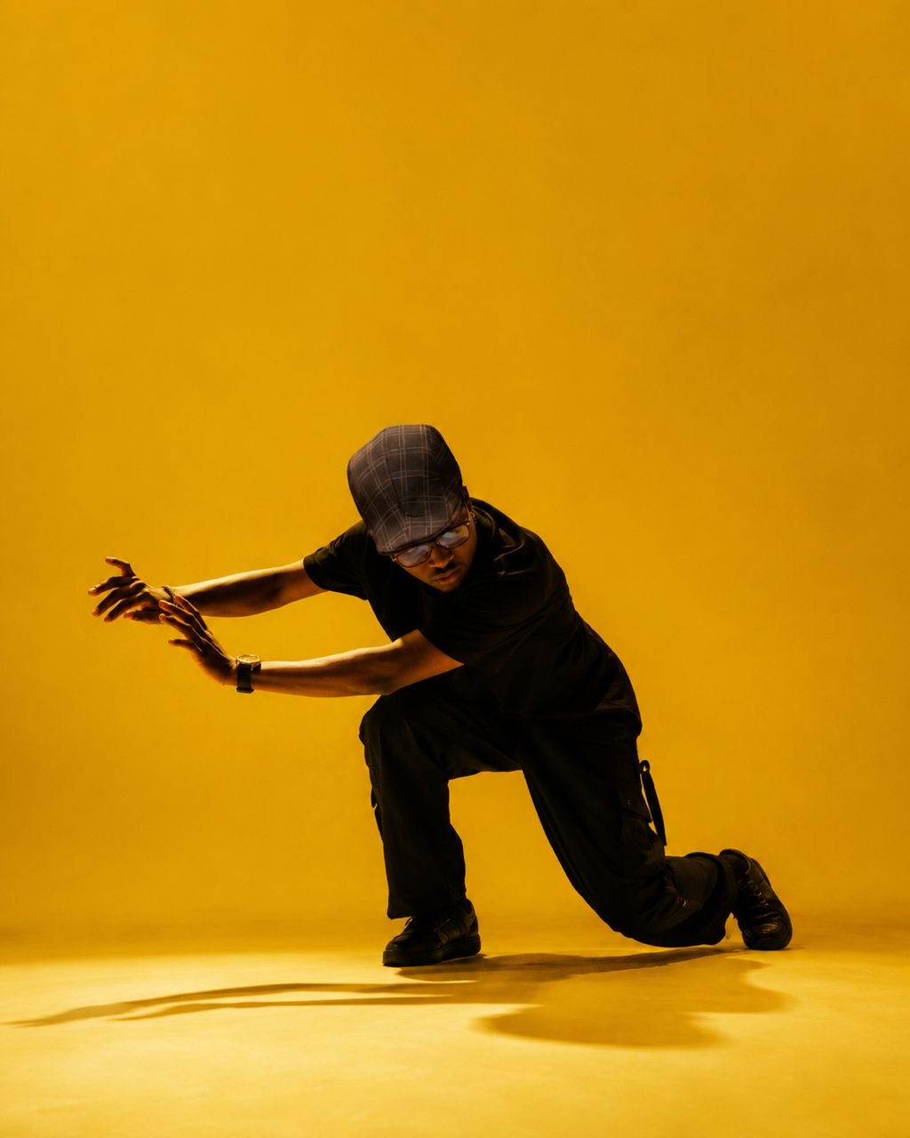 Olaibi Olalekan Moses performing a dance move against a vibrant yellow background